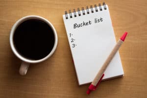 Bucket list, red pen, and coffee by notebook